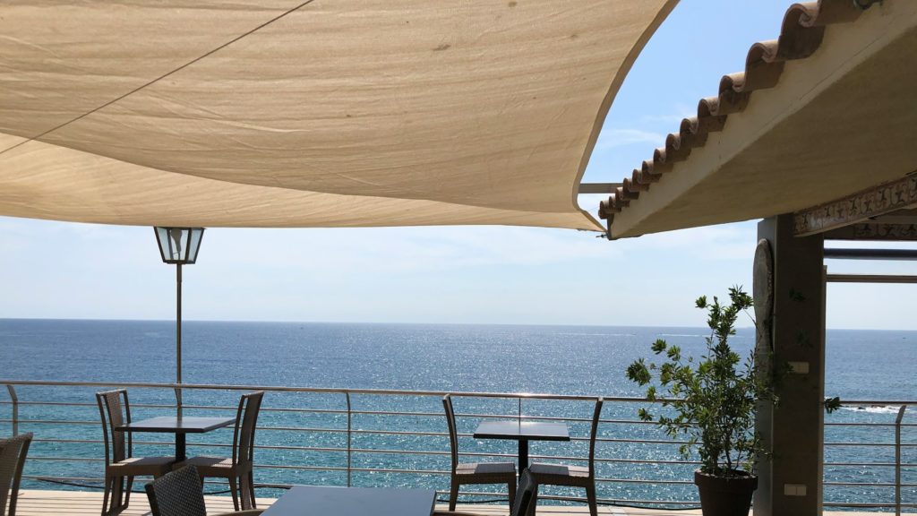 brown wooden table and chairs near sea during daytime
